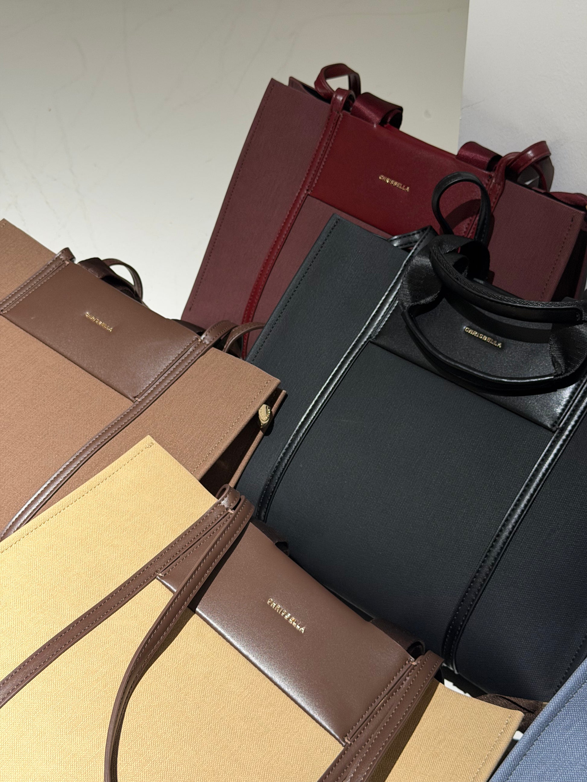 A collection of luxury handbags from Balenciaga, including a black leather tote with a gold logo, a dark red leather tote, and several brown and beige textured satchels, arranged closely together.